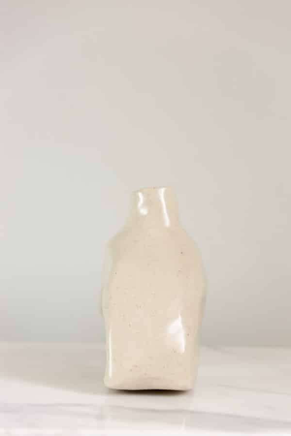 Small hand-built beige ceramic vase this is uniquely curved and a side view